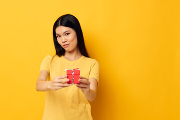 Portrait Asian beautiful young woman holding a gift box in his hands posing yellow background unaltered