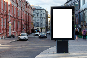 Vertical billboard near the road in the city. Lane, evening, townspeople. Mock-up.