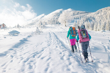 Fototapeta na wymiar Two women walk with snowshoes on the backpacks in winter trekking