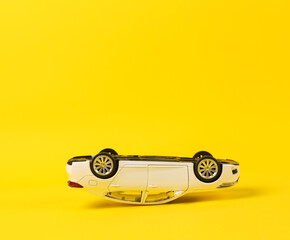 Upside down model of a toy car on a yellow background. Car accident © splitov27