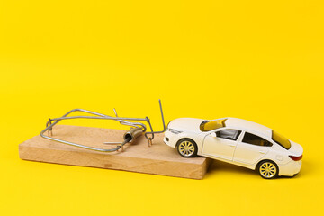 Toy car model with a mousetrap on a yellow background. Hidden problems when buying car
