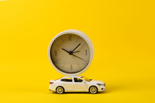 Toy car model with clock on yellow background