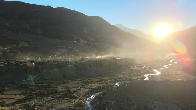Aerial view looking at Manang village in Nepal along the Marsyangdi River as the sun peaks over the mountains.