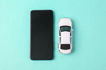 Toy car model with smartphone on blue background.