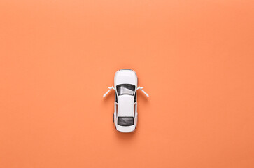 Toy car model with open doors on pink background. Top view