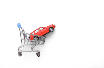 Buying a car concept. Shopping cart with toy car model on white background