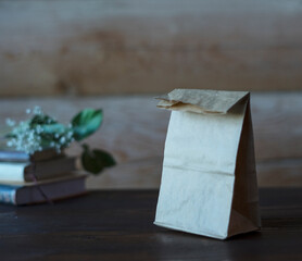 Craft and rustic paper bag mock up for your illustration and design, at rustic wooden background. Blank craft paper bag
