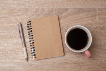 Cup of coffee with notepad on the table. Top view