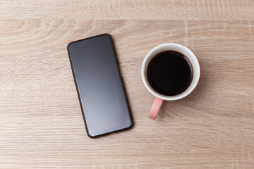 Fototapeta na wymiar Cup of coffee with smartphone on table
