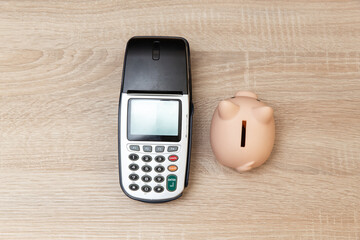 Piggy bank with Payment pos terminal on wooden table