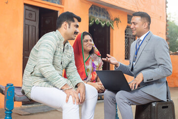 Real estate agent or financial advisor with laptop meeting rural Indian couple, Male bank manager...