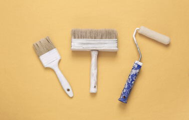 Paint brushes and roller on yellow background. Repair symbol