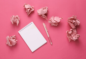 Notebook with crumpled paper balls on pink background