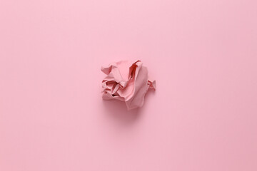 Pink crumpled paper ball on pink background