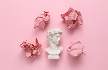 David bust with crumpled paper balls on pink background. Minimal layout