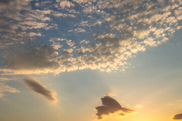 Beautiful sunset sky with feathery clouds on a blue background with yellow sunlight