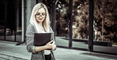 busy blonde business woman with folder at office building