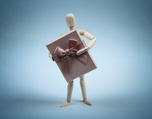 Wooden puppet holding gift box isolated on bliue background