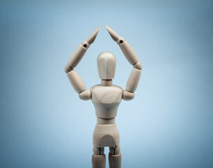 A wooden puppet holds arms above its head. Protection concept