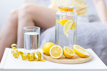 Healthy drink - water with lemon. Female drinking from the glass on background. Concept of clean...