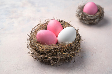 Three Easter eggs in a nest on a light background.