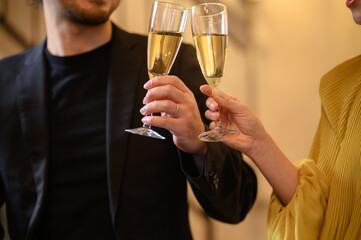 Image of a man and woman toasting at a bar. Close-up of hands.