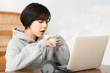 コーヒーを飲みながらパソコンの仕事をする女性