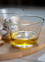 A glass with olive oil with garlics and black pepper on a cutting board as part of kitchen ingredients, Macro photography.