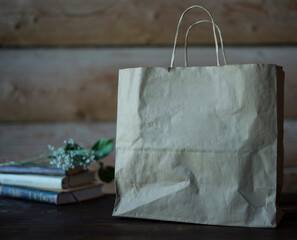Craft and rustic paper bag mock up for your illustration and design, at rustic wooden background. Blank and empty craft paper bag