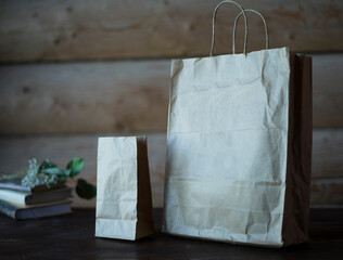 Craft and rustic paper bag mock up for your illustration and design, at rustic wooden background. Blank and empty craft paper bag