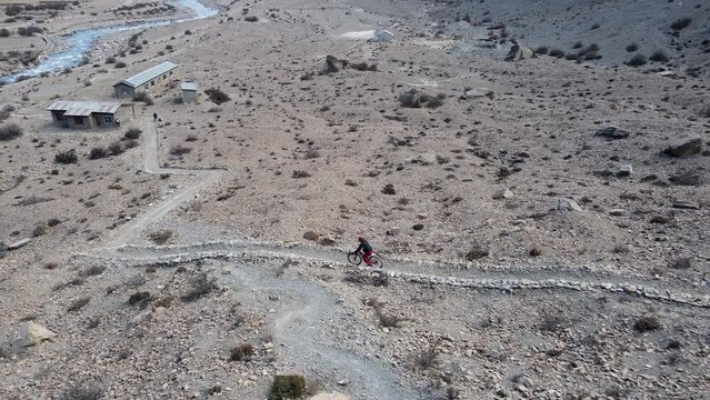 Aerial view of person mountain biking down trail in Manang Nepal.