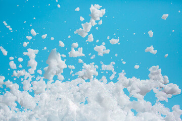 Fototapeta na wymiar White soap foam on a blue sky background. Fun foam, background or texture of a white foam with copy space Entertainment foamy parties a summer entertainment festival in the water park