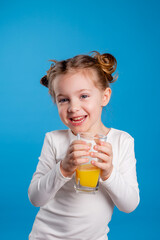 little girl with a funny hairstyle in a white T-shirt holds a glass with juice in her hands