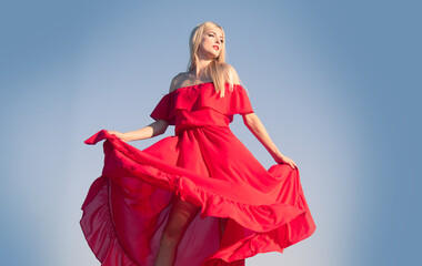 Woman in red dress movement on sky. Fashionable young model in style dress. Fashion woman in summer.