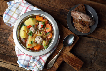 Homemade rustic soup with meatballs, peas, carrots, potatoes, onions, garlic, chili and parsley