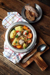 Homemade rustic soup with meatballs, peas, carrots, potatoes, onions, garlic, chili and parsley