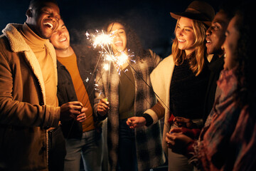 Group of young adult Multi-cultural friends laughing at a rooftop party with sparklers
