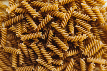 pasta close-up in full screen. raw whole grain fusilli pasta macro photo. spiral pasta top view