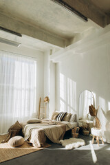 bedroom interior with white walls and large windows with white tulle. spacious bright bedroom filled with natural light. loft room with high ceilings and plenty of blankets and pillows on the bed.	
