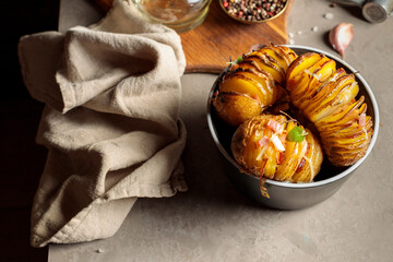 Baked potatoes stuffed with bacon, cheese and herbs. Horizontal frame on a gray table, with a linen napkin.Low key.