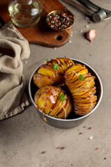 Whole baked potatoes with herbs and spices. On a gray background, with kitchen utensils. Vertical. Low Key