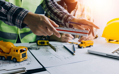 Concept architects, engineer holding pen pointing equipment architects On the desk with a blueprint in the office, Vintage, Sunset light.Selective Focus