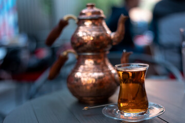 Turkish traditional tea in tulip-shaped glass with cupper colored double teapot