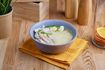 Delicious dietary chicken soup with noodles on the table in the composition
