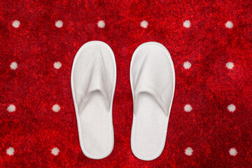 White slippers on red carpet with white dots background