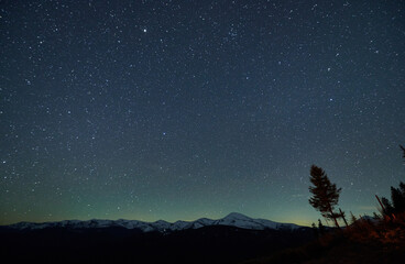 Magic starry night in the mountains. Beautiful winter landscape of snow-capped mountain beskids....