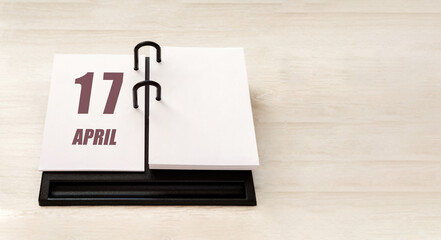 April 17. 17th day of month, calendar date. Stand for desktop calendar on beige wooden background. Concept of day of year, time planner, spring month