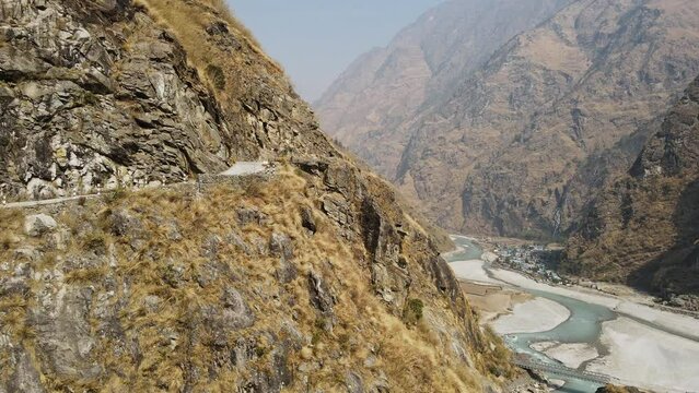 Truck driving on road carved into mountain side along the Marsyangdi River flying through the canyon in Nepal.