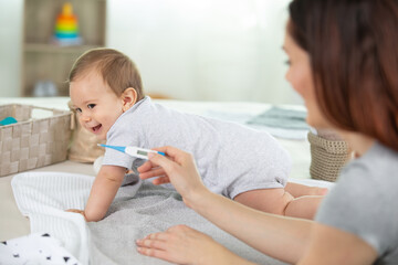 woman measuring temperature of small sick boy