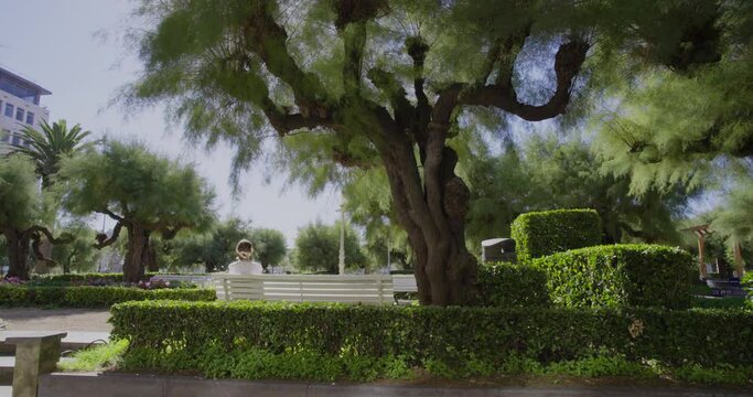 Holiday concept. The girl sitting back Look at the nature in the Alderdi Eder Park. 4k Resolution.